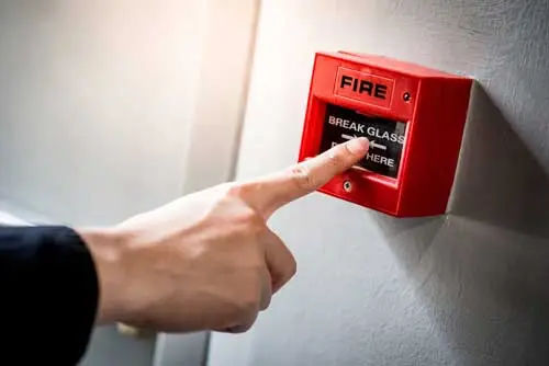 Fire marshal pressing fire call point  as part of regular testing