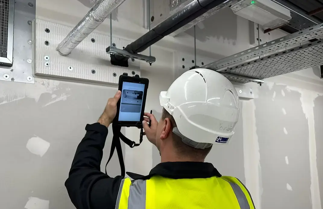 A Man in hi vis vest maintaining a fire door